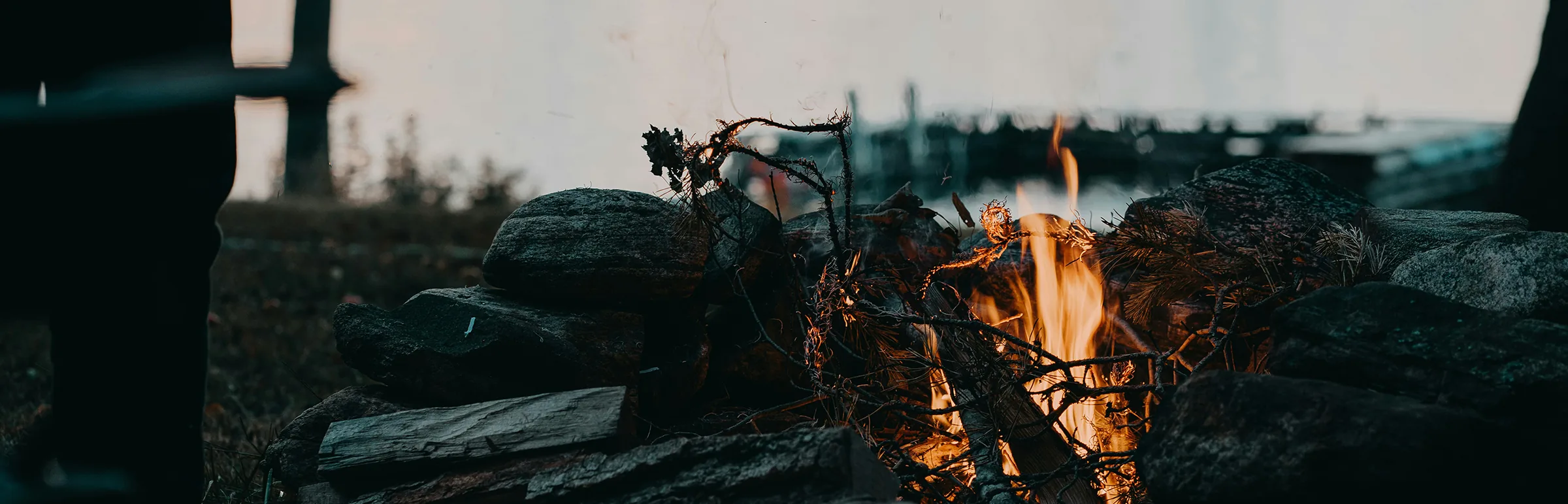 Feu de camp au bord d'un lac de montagne, à la tombée du jour