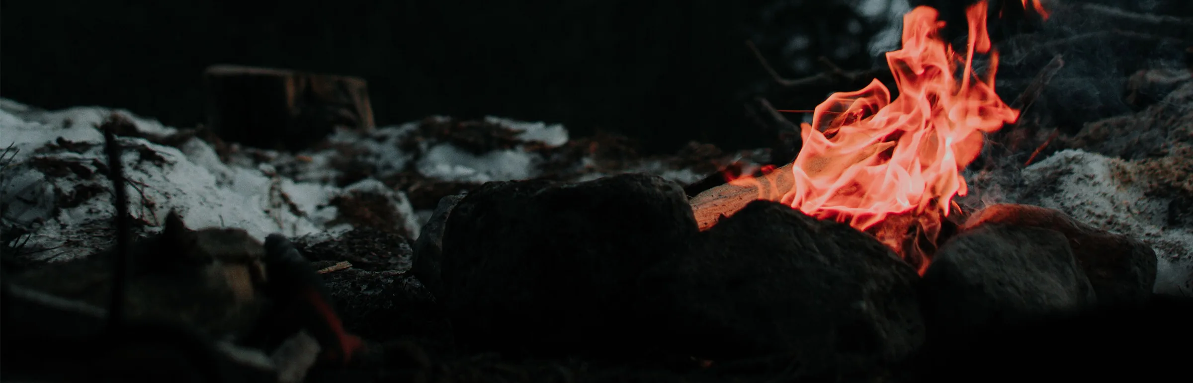 Flammes d'un feu de camp la nuit, entre pierres et neige