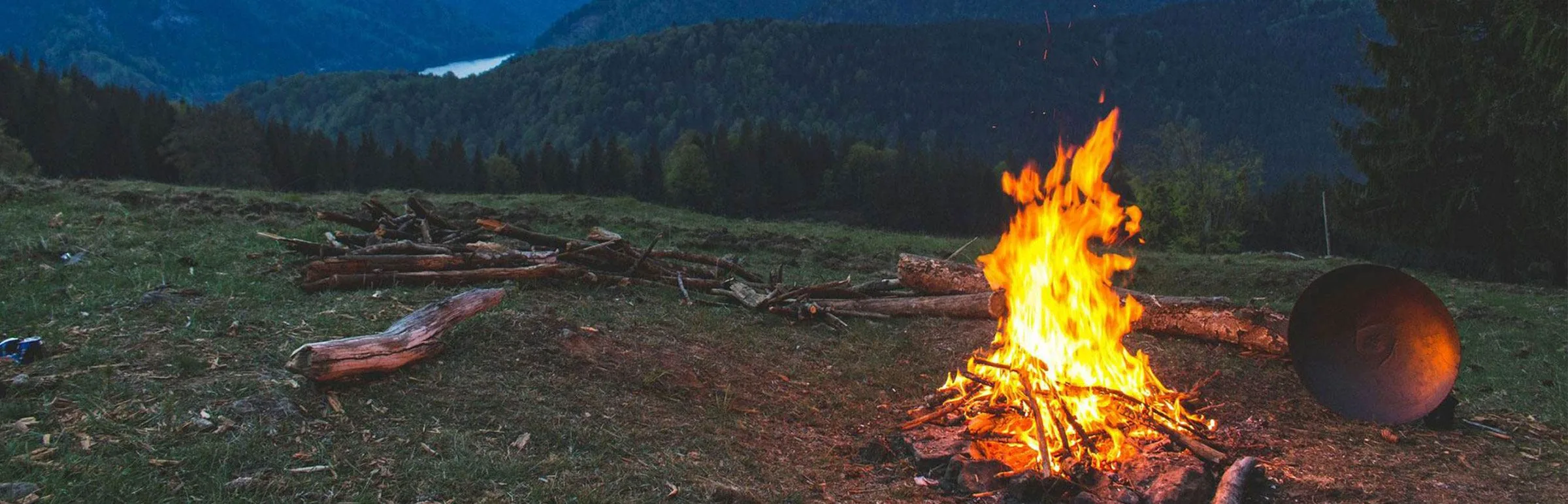 Feu de camp partagé entre amis, au crépuscule en montagne